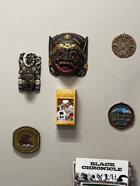 Carved masks and decorative wall artefacts above a Black Chronicle publication.