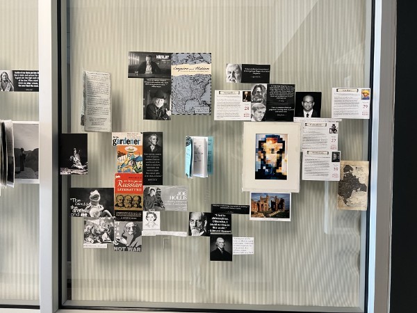 Printed quotations, book covers, maps, and photographs arranged across a glass window.