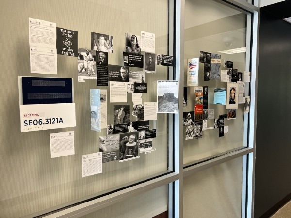 Two glass panels covered with historical portraits, quotations, and short readings beside a hallway.