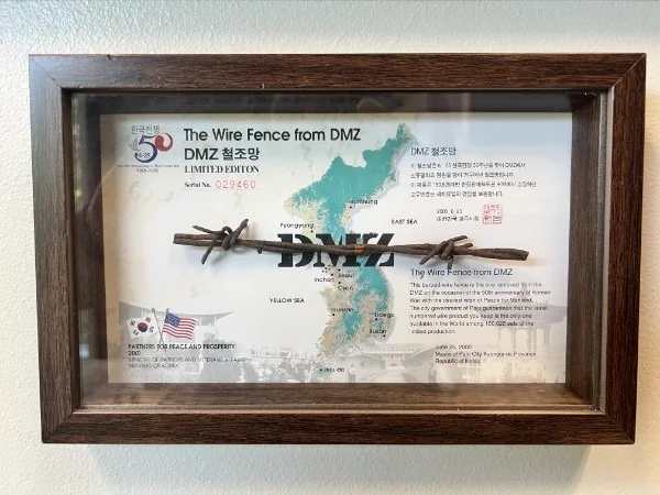 A framed display labeled “The Wire Fence from DMZ,” with a wire fragment and map.