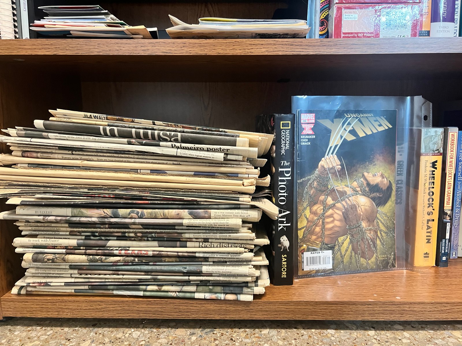 A stack of newspapers and periodicals beside books on a shelf in the Center.