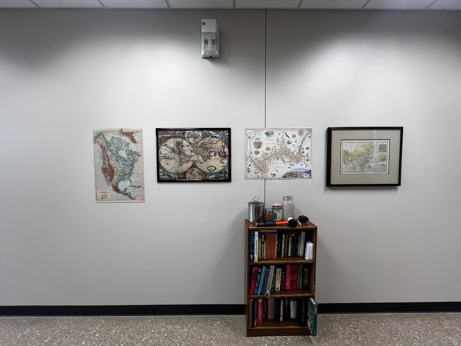 Framed historical puzzles displayed above a small bookshelf at the Center.